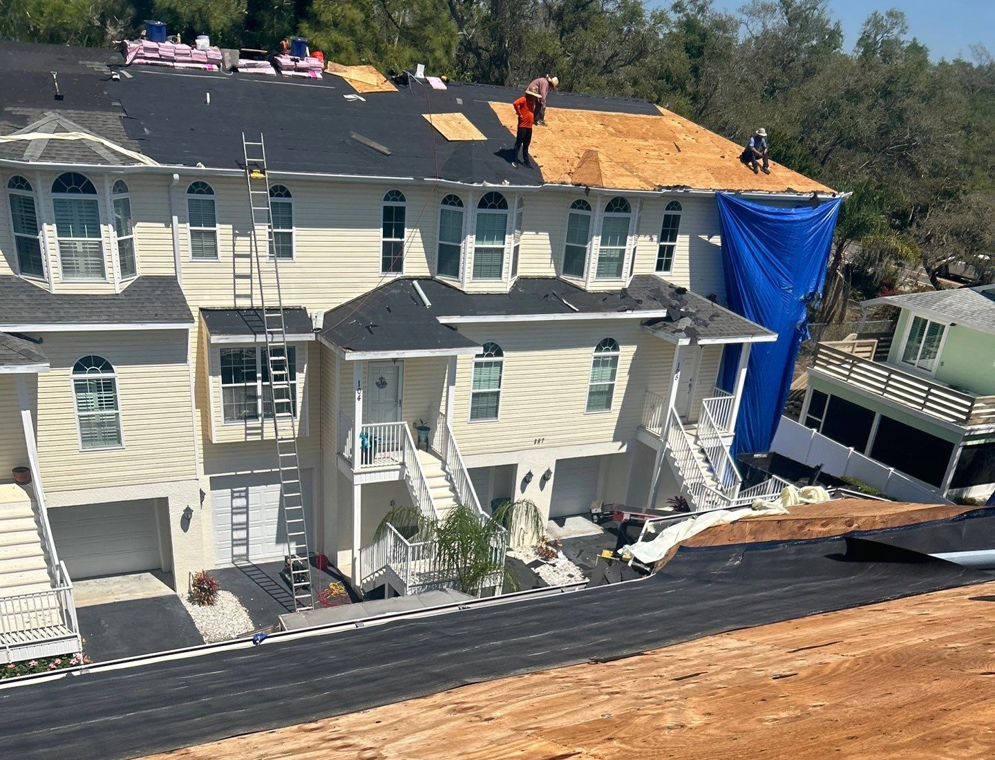 Roofing crew installing new shingles on a large apartment complex.